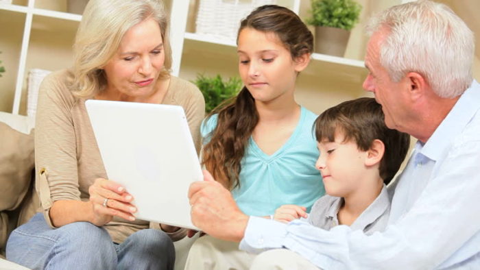 Grandparents and their grandkids looking into a computer device