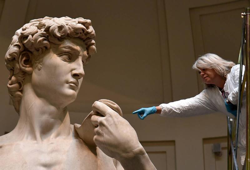An art restorer works on cleaning Michelangelo's David, one of the world's most famous statues, on February 29, 2016 at the Galleria dell'Accademia in Florence
