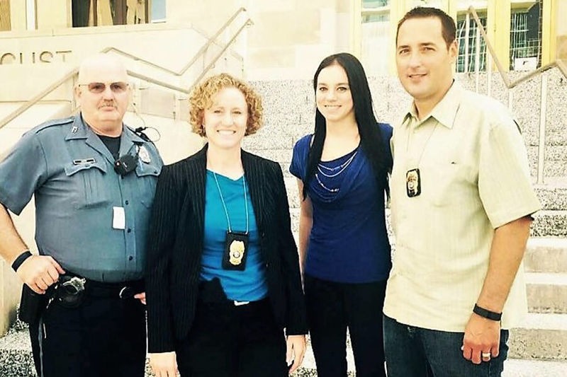 Tres oficiales policiales con una mujer de cabello negro y blusa azul